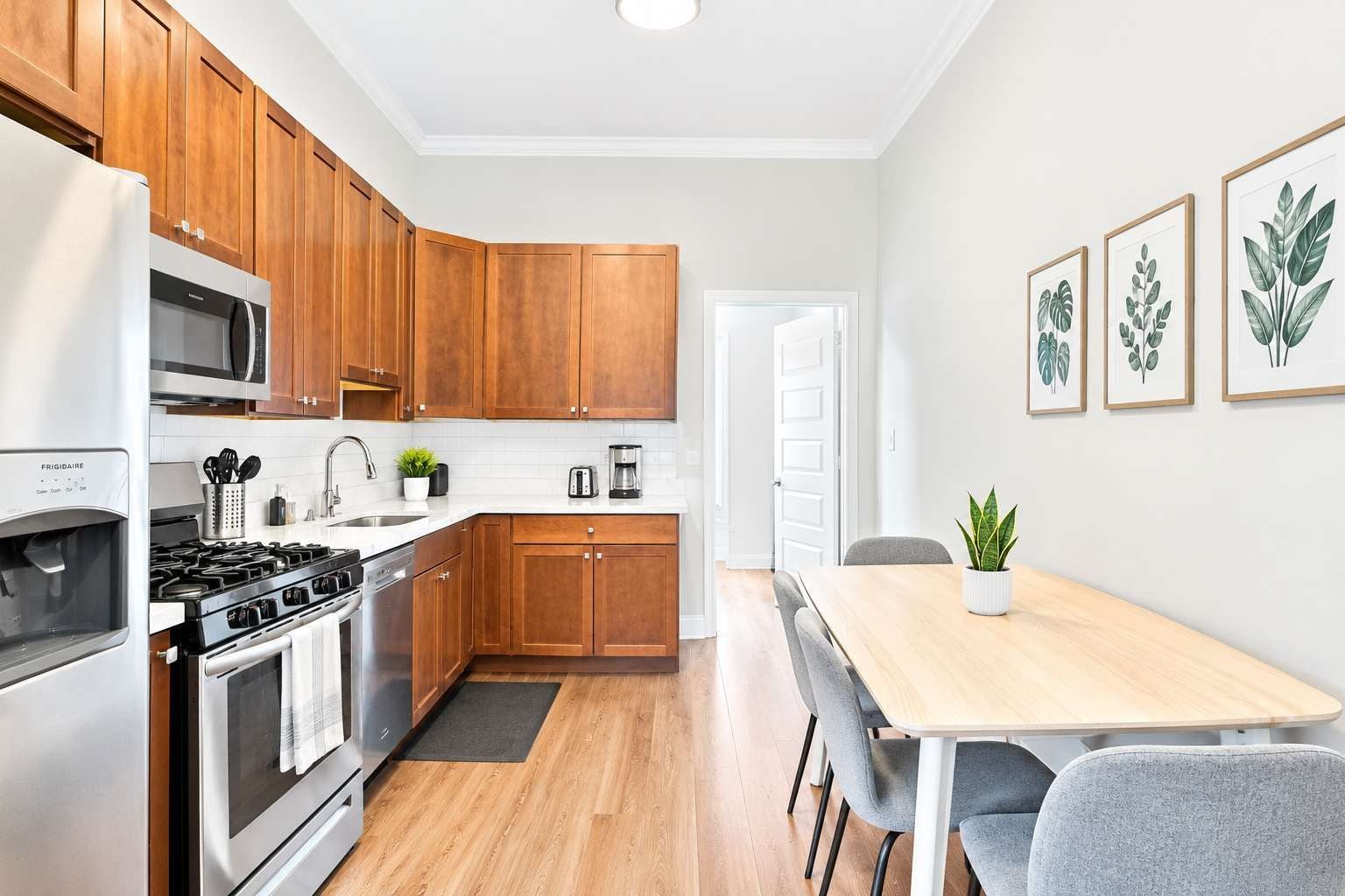 A modern kitchen with wooden cabinets, stainless steel appliances, and a dining area with a table and chairs.