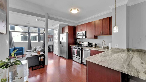 A modern kitchen with wooden cabinets, stainless steel appliances, and a large island.