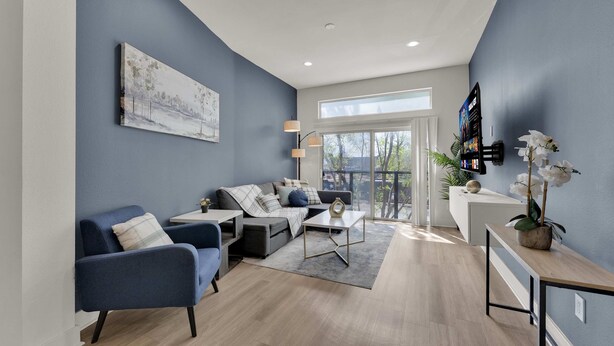 A modern living room with a sofa, armchairs, a coffee table, and a TV mounted on the wall. - Luxury Modern 2BR Sleeps 8 | near Fair Park Dallas (Dallas)