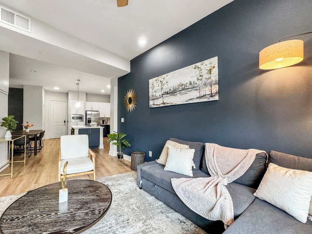 A modern living room with a grey sofa, a round coffee table, and a painting on the wall.