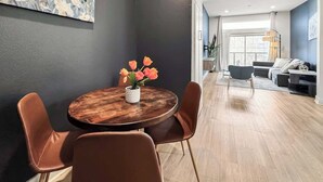 Un salon moderne avec une table ronde en bois, des fauteuils en cuir et un vase de fleurs.