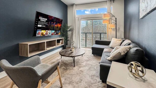 Un salon moderne avec un téléviseur à écran plat, un canapé, une table basse et un escalier.
