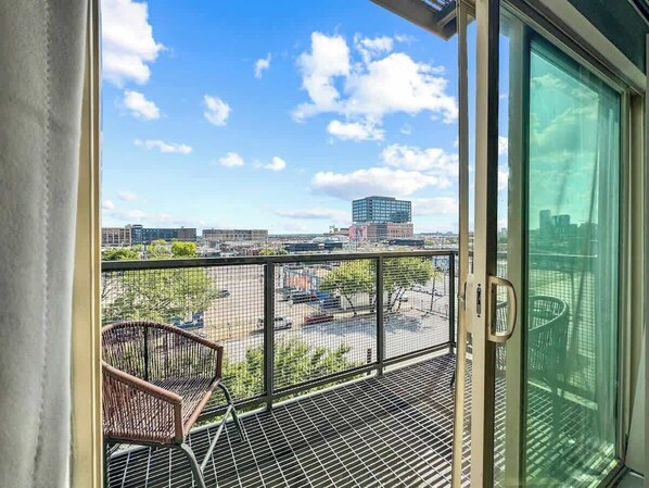 A balcony with a view of a parking lot and buildings.