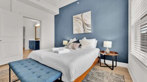 Un dormitorio moderno con una cama grande, mesitas de noche y una pared azul de acento.