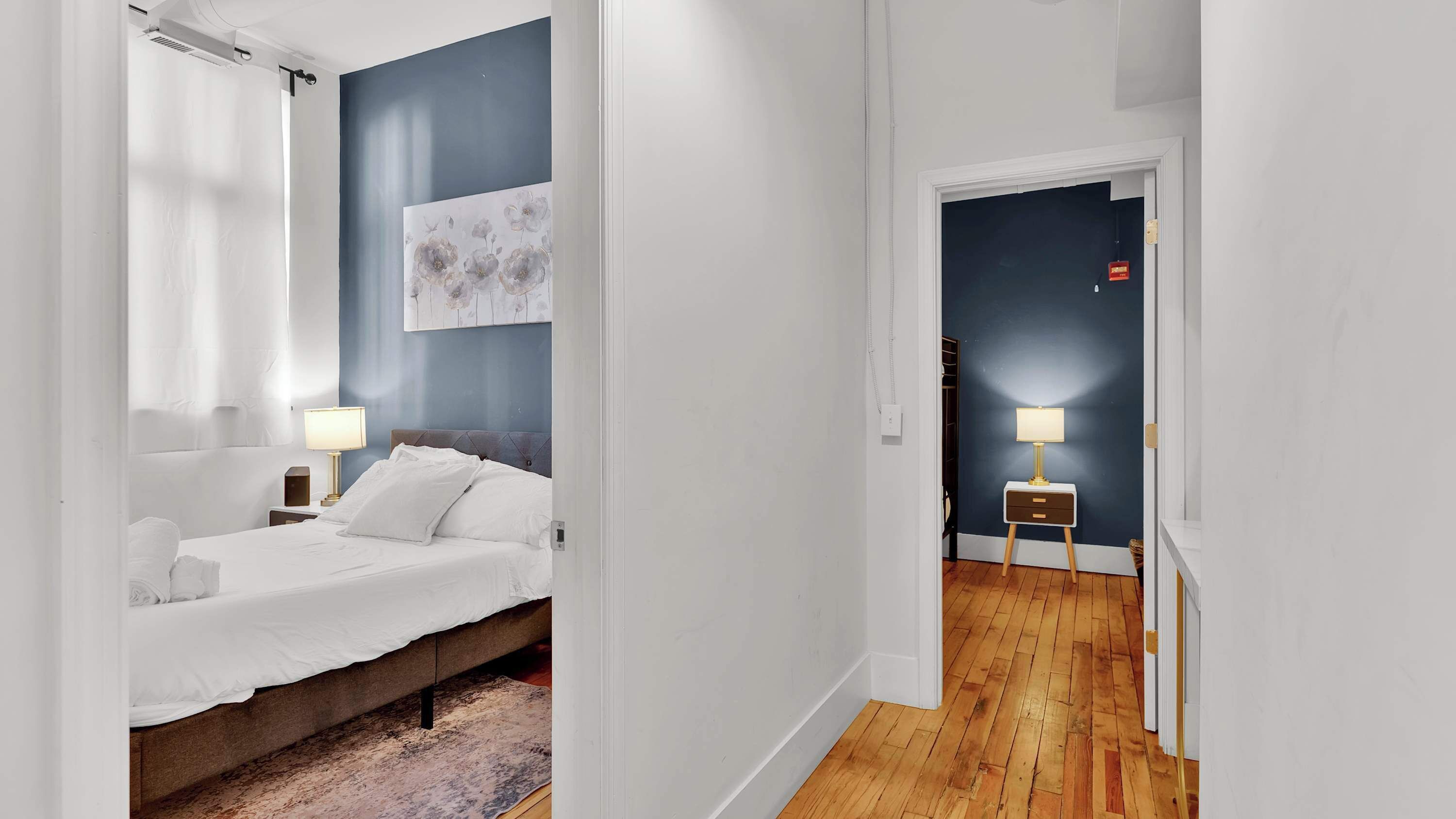 Une chambre à coucher avec un lit, une table de chevet, une lampe et un tableau au mur.