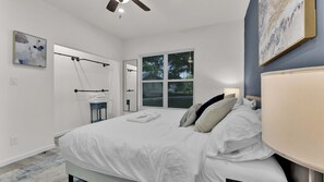A bedroom with a bed, a nightstand, a window, and a ceiling fan.