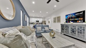 A modern living room with a sofa, coffee table, and a TV mounted on the wall.