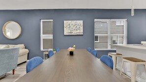 A conference room with a long table, chairs, a small table with a plant, and a painting on the wall.