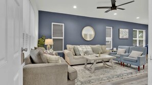 A living room with a sofa set, a coffee table, a blue armchair, and a ceiling fan.