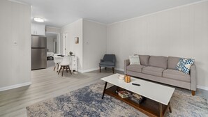 A modern living room with a beige sofa, a white coffee table, and a blue patterned rug. - Stylish & Cozy 1BR Apt Near Duke, Downtown Durham, Dining & Entertainment (Durham)