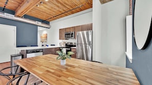 Une cuisine moderne avec une table en bois, des appareils en acier inoxydable et un mur d’accent bleu.