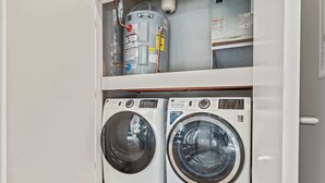 A compact laundry area with two front-loading washing machines and a water heater above them. - Luxury 1BD | 1 Bed | Northern Liberties (Philadelphia)