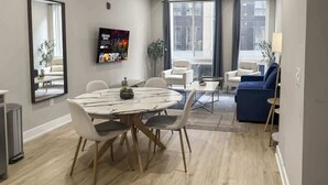 A modern hotel room with a dining area, a large window, and a TV mounted on the wall. - Luxury 1BD | 2 Beds | Northern Liberties (Philadelphia)