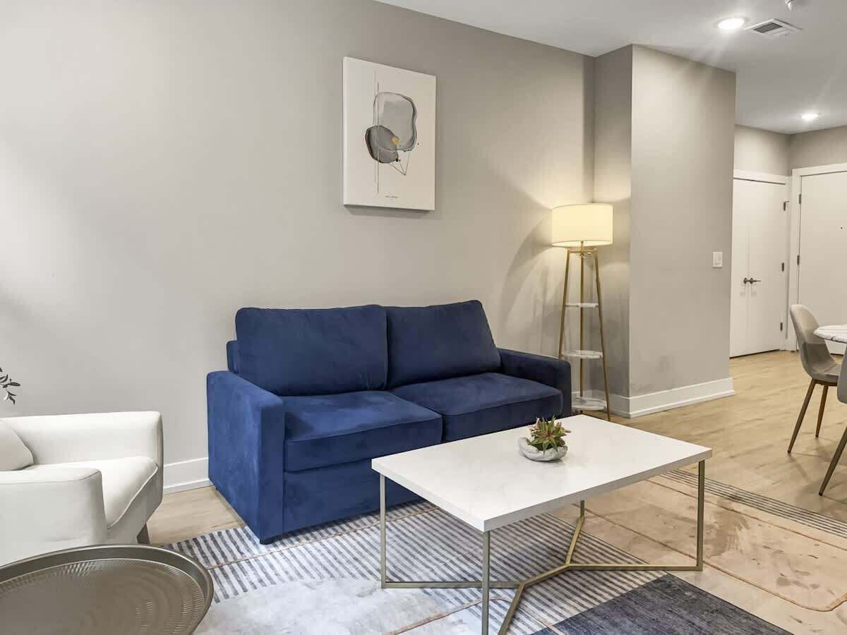 A modern living room with a blue sofa, a white coffee table, and a floor lamp.