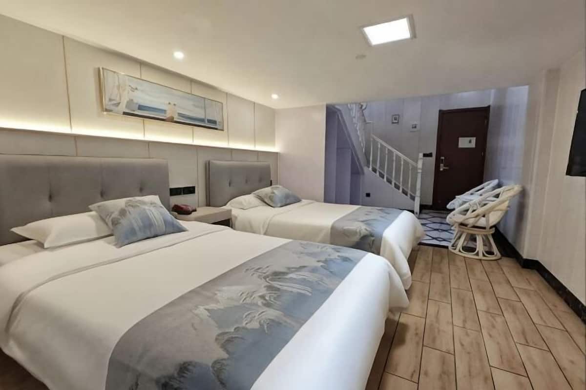 A hotel room with two beds, a massage chair, a staircase, and a door.