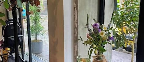 Una mesa de comedor con una ensalada, un jarrón de flores y un vaso de agua.