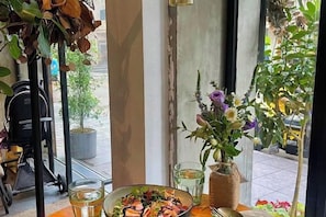 A dining table with a salad, a vase of flowers, and a glass of water. - Longchen Holiday Inn (Shanghai Ruijin Hospital Yongjia Road Branch) (Shanghai)
