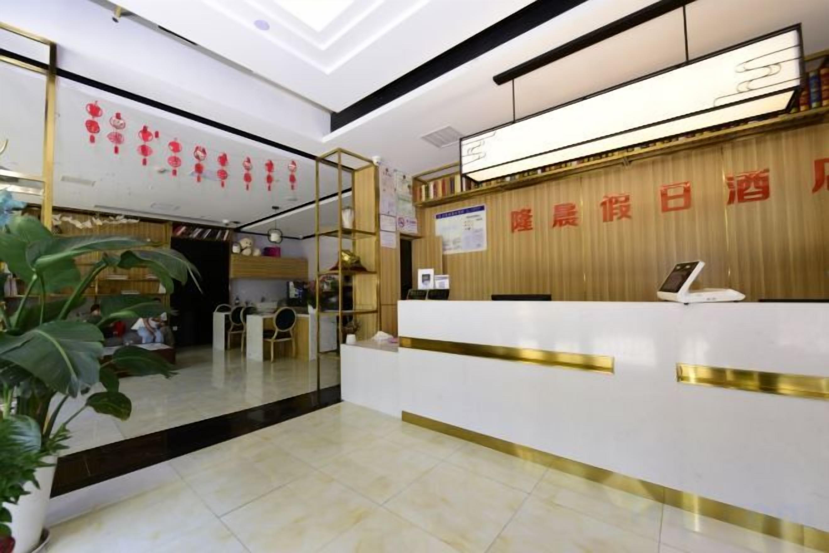 A hotel reception area with a reception desk, a digital screen, and a wooden wall with red text.