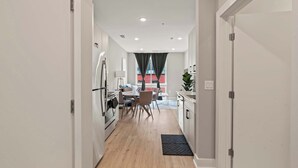 A modern kitchen with white cabinets, a dining area with a table and chairs, and a view of a red building outside.