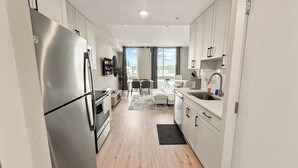A modern kitchen with stainless steel appliances, a dining area with a table and chairs, and a view through the window. - Luxury Studio | 1 Bed | Northern Liberties (Philadelphia)