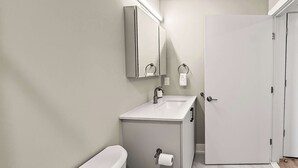 A modern bathroom with a toilet, sink, and mirror. - Luxury Studio | 1 Bed | Northern Liberties (Philadelphia)