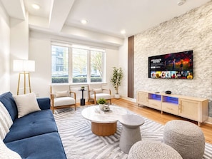 Uma sala de estar moderna com sofá, cadeiras, mesa de centro e TV fixada em uma parede com textura.
