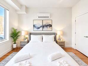 Habitación de hotel con una cama grande, dos mesitas de noche, una planta en maceta y cuadros en la pared.