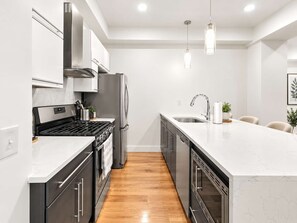 Una cocina moderna con electrodomésticos de acero inoxidable, encimera de mármol y suelo de madera.