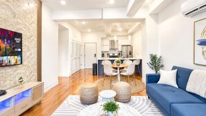 A modern living room with a blue sofa, a marble coffee table, and a kitchen in the background.