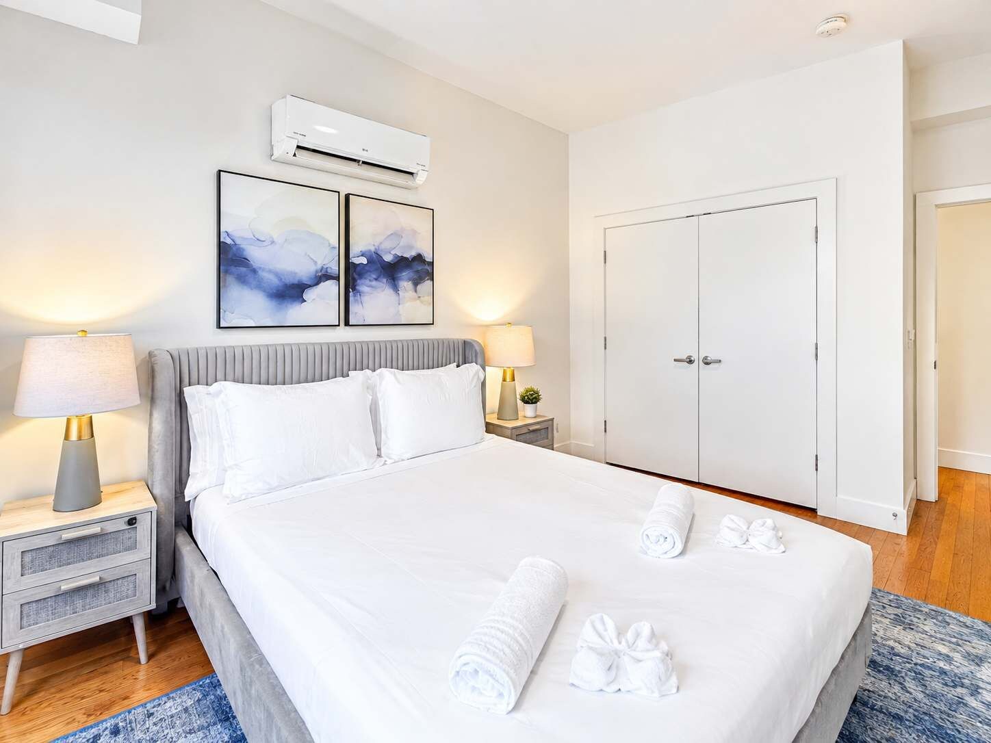 Una camera d'albergo con un letto, comodini, un armadio e opere d'arte appese al muro.