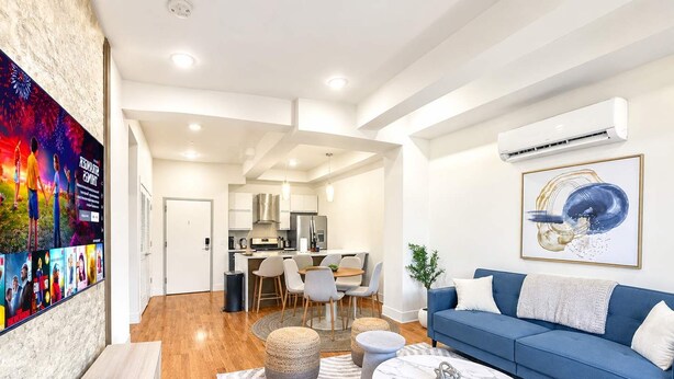 A modern living room with a blue sofa, a coffee table, and a TV mounted on the wall.