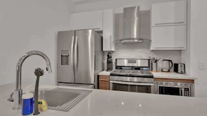 Una cucina moderna con elettrodomestici in acciaio inossidabile, forno integrato e macchina per il caffè.