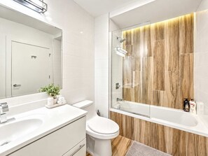 A modern bathroom with a large mirror, a white sink, a toilet, and a glass-enclosed shower area. - Modern Philly Haven | 1BD | Sleeps 4 | Northern Liberties (Philadelphia)