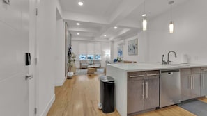 A modern kitchen with a central island, stainless steel appliances, and a view to the living area.