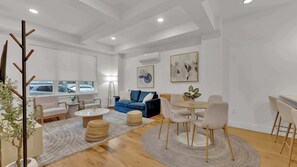 Un salon moderne avec un canapé bleu, une table basse ronde et un coin repas comprenant une table et des chaises en bois.