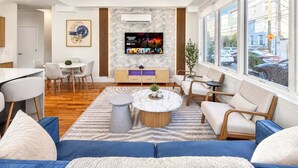 A modern living room with a TV, seating, and a view of the street.