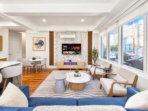 A modern living room with a TV, seating, and a view of the street.