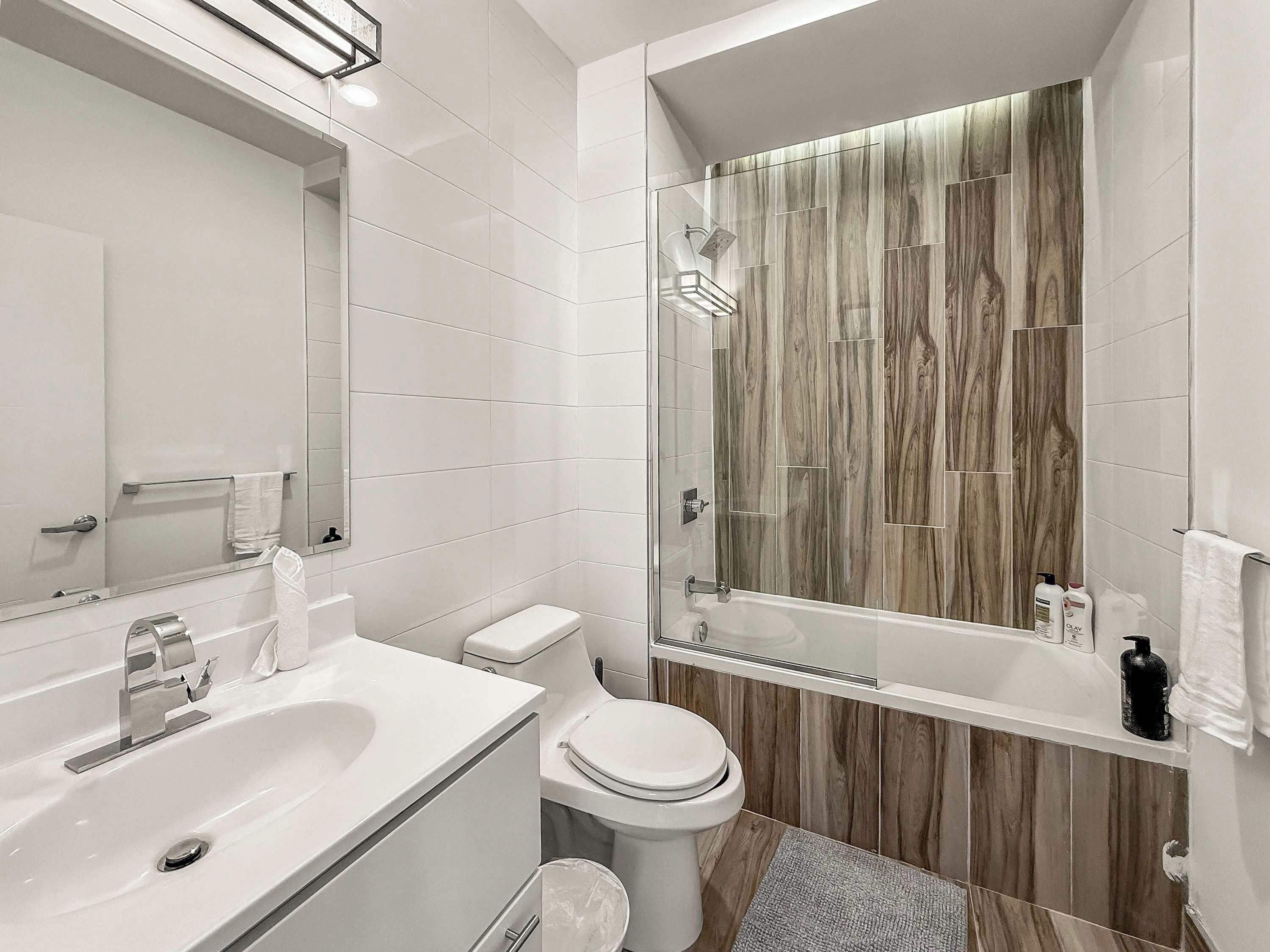 A modern bathroom with a white sink, toilet, and shower area.