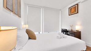 Une chambre d’hôtel avec un lit, un bureau, une lampe et un tableau au mur.