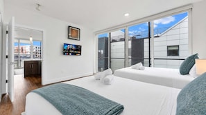 A hotel room with two beds, a TV, and a view of the city.