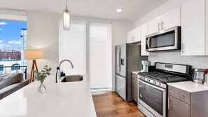A modern kitchen with a central island, stainless steel appliances, and a view to the outside.