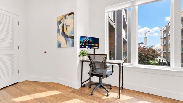 Une pièce avec un bureau, une chaise et une grande fenêtre.
