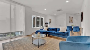 A modern living room with a sectional sofa, a glass coffee table, and a blue armchair.