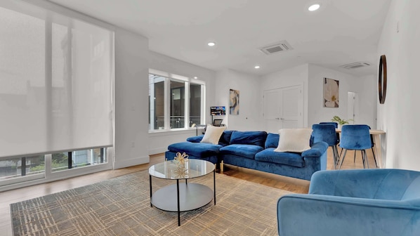 Una sala de estar moderna con un sofá modular, una mesa de centro de vidrio y un sillón azul.