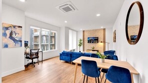 Un salon moderne avec un canapé, une table à manger et un téléviseur fixé au mur.