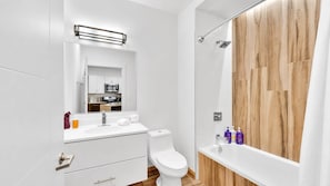 A modern bathroom with a white sink, toilet, and shower area.