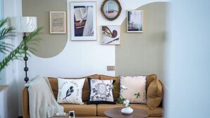 A living room with a brown sofa, a round coffee table, and framed pictures on the wall. - Qingxu Jinrui 99 Boutique Hotel (Qingxu)