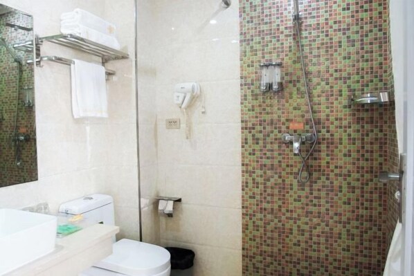 Un baño con ducha, inodoro, lavabo y espejo.