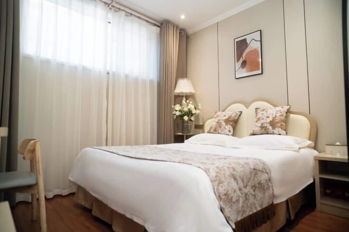 Una camera d'albergo con un letto, una sedia, un comodino, una lampada e un quadro appeso al muro.
