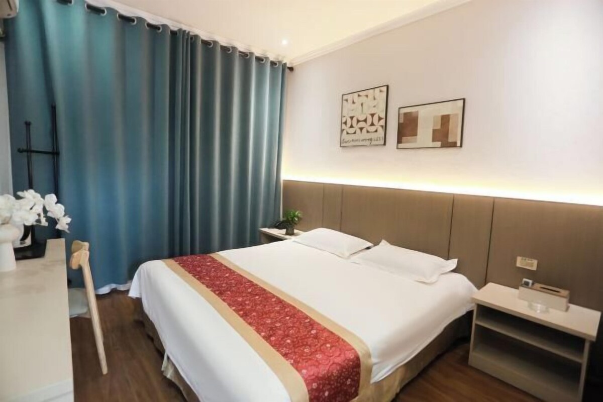 A hotel room with a bed, a nightstand, a desk, and a chair.